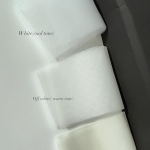 May include: Three swatches of sheer tulle fabric arranged vertically. The top swatch is labeled White (cool tone), the middle swatch is labeled Off white (warm tone), and the bottom swatch is labeled Ivory. A red tag with the text white is visible.