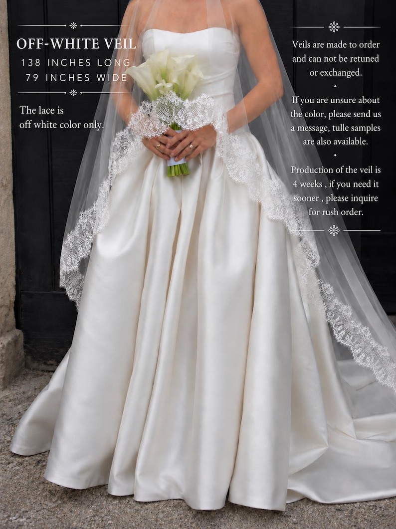 May include: An off-white veil measuring 138 inches long and 79 inches wide, featuring intricate lace trim along the edges. The veil is worn over a solid off-white strapless gown, and the lace is off-white. Text includes OFF-WHITE VEIL.