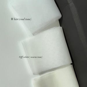 May include: Three swatches of sheer tulle fabric arranged vertically. The top swatch is labelled White (cool tone), the middle swatch is labelled Off white (warm tone), and the bottom swatch is labelled Ivory. A red tag with the text white is visible.