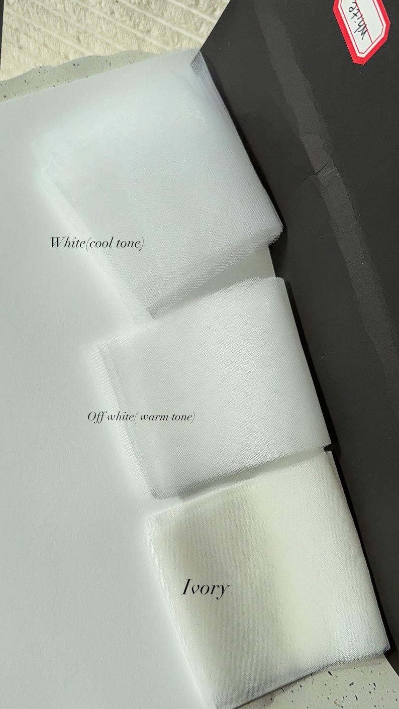 May include: A close-up of three fabric swatches in shades of white. The top swatch is labelled "White (cool tone)", the middle swatch is "Off white (warm tone)", and the bottom swatch is "Ivory". The fabrics are layered and folded.