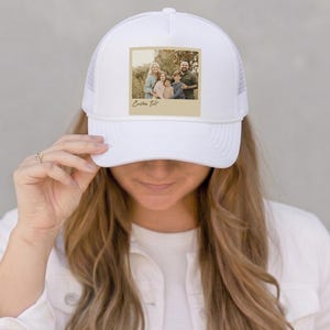 May include: White trucker hat with a family photo on the front. The photo is in a vintage style with a beige border and the words "Custom Text" below the photo. The hat has a mesh back.