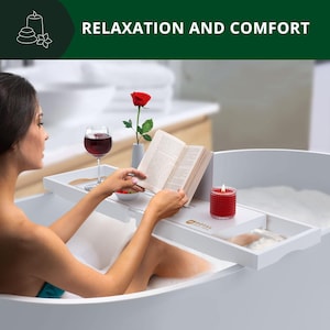 Puede incluir: Una bandeja blanca para bañera sostiene una copa de vino tinto, un libro, una vela roja y un pequeño jarrón con una rosa roja. La bandeja está en una bañera blanca con una persona relajándose en el agua. El texto "RELAXATION AND COMFORT" está en la parte superior.