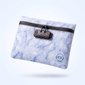May include: A rectangular pouch with a light blue and white marble pattern, featuring a black horizontal zipper and a black TSA007 combination lock. The pouch displays the circular logo SZ STASHEEZE in blue and has small water droplets on the surface.