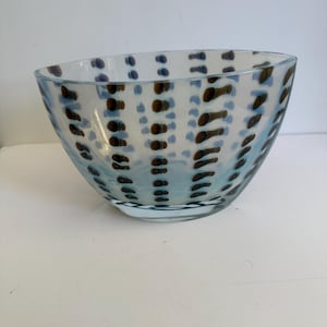 May include: A clear glass bowl with a square shape and a light blue tint. The bowl is decorated with a pattern of brown and blue dots. The bowl is likely used for serving food or as a decorative item.