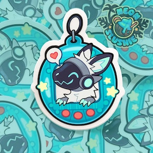May include: A sticker featuring a teal-colored, circular design with a cartoon character inside. The character has a black face, white fur, and teal accents. A red heart icon is above the character. The sticker has a white border.