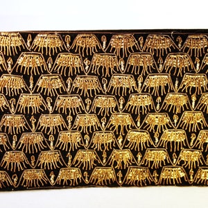 May include: A black velvet clutch bag with a gold beaded pattern. The pattern is a repeating design of stylised trees or plants.
