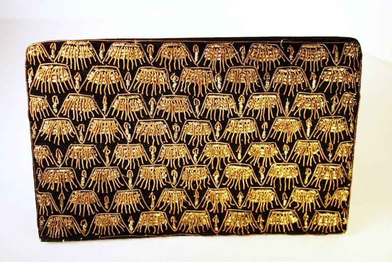 May include: A black velvet clutch bag with a gold beaded pattern. The pattern is a repeating design of stylised trees or plants.