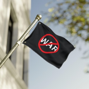 May include: A black flag with the word "WAR" inside a red circle with a red slash through it. The flag is attached to a gold pole and is waving in the wind. The background includes a building and a blue sky.