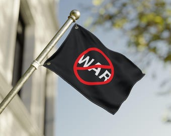 Könnte beinhalten: Eine schwarze Flagge mit dem Wort „WAR“ in einem roten Kreis mit einem roten Strich. Die Flagge ist an einer goldenen Stange befestigt und weht im Wind. Der Hintergrund umfasst ein Gebäude und einen blauen Himmel.