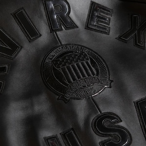 Detailed close-up shot of premium black lambskin leather material showing the soft grain texture, precision stitching, and heavy-duty zipper.