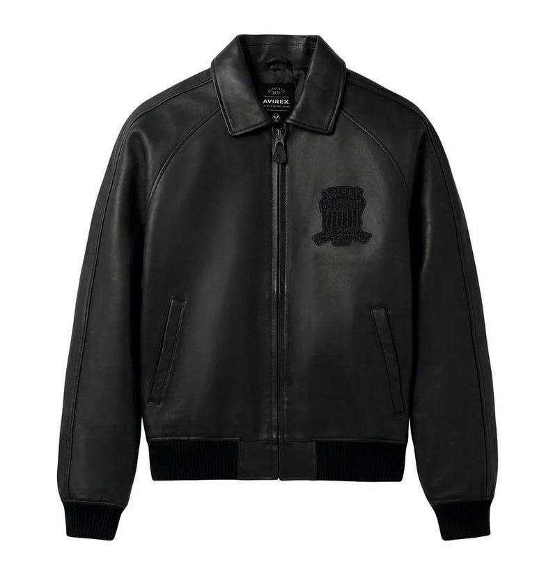 Front view of a handmade men's black lambskin leather bomber jacket with a metallic front zipper, classic side pockets, and ribbed cuffs.