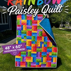 May include: A rectangular quilt featuring a vibrant patchwork of multicolored paisley fabric squares in red, orange, yellow, green, blue, and purple. The quilt measures 48 inches by 60 inches and has a solid blue backing with white edge binding.