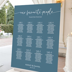 Peut inclure: Panneau de plan de table de mariage bleu poussiéreux avec le texte "our favorite people" et les noms des invités par numéro de table. Les noms sont en écriture blanche sur fond bleu. Les noms du couple, Ashley & Daniel, et la date du mariage sont en bas.
