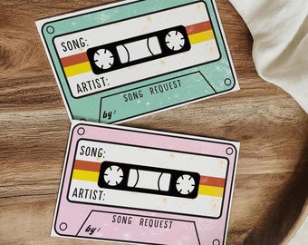 Könnte beinhalten: Zwei leere Kassetten-Song-Anforderungs-Karten. Die obere Karte ist hellblau mit einem gelben und orangefarbenen Streifen. Die untere Karte ist rosa mit einem gelben und orangefarbenen Streifen. Beide Karten haben den Text "SONG REQUEST" aufgedruckt.