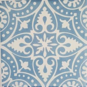 May include: A blue and white ceramic tile with a repeating geometric pattern. The tile features a central design of a stylized flower with four petals, surrounded by a repeating pattern of leaves and swirls.