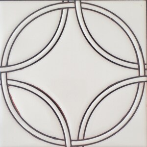 May include: White ceramic tile with a black geometric design of overlapping circles.
