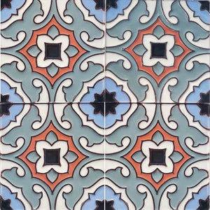 Op de afbeelding: Vier vierkante keramische tegels die samen zijn gerangschikt en een herhalend patroon vertonen. Het ontwerp omvat een centrale oranje bloemvorm met een zwart vierkant midden, omgeven door witte, blauwe en blauwgroene accenten. De tegels hebben een glanzende afwerking.