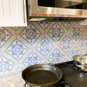 Pode incluir: Azulejos de cozinha com padr&otilde;es azuis e brancos. Uma frigideira preta est&aacute; sobre um fog&atilde;o, com um micro-ondas de a&ccedil;o inoxid&aacute;vel por cima. Um arm&aacute;rio branco &eacute; vis&iacute;vel &agrave; esquerda.