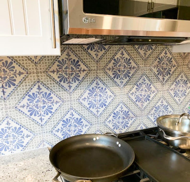 Pode incluir: Azulejos de cozinha com padr&otilde;es azuis e brancos. Uma frigideira preta est&aacute; sobre um fog&atilde;o, com um micro-ondas de a&ccedil;o inoxid&aacute;vel por cima. Um arm&aacute;rio branco &eacute; vis&iacute;vel &agrave; esquerda.