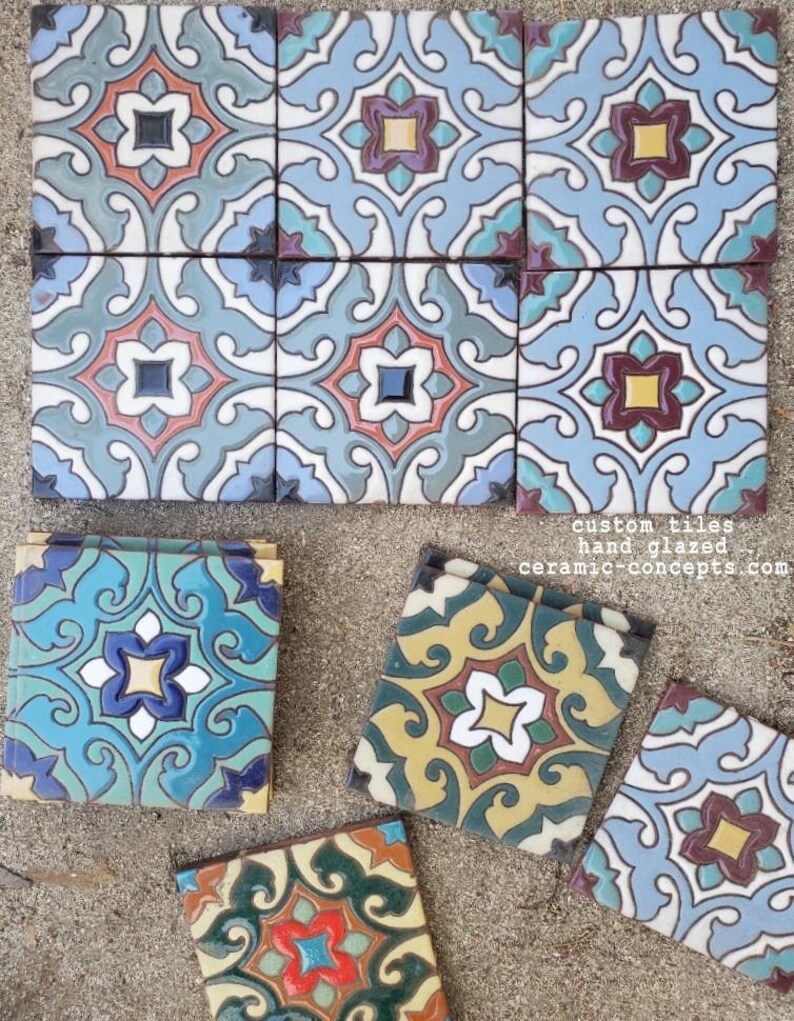 Op de afbeelding: Handgeglazuurde, op maat gemaakte keramische tegels met ingewikkelde bloemen- en geometrische patronen in tinten blauw, blauwgroen, geel en rood. De tegels zijn gerangschikt in een raster en verspreid. Tekst op de tegels luidt: custom tiles hand glazed ceramic-concepts.com.