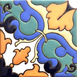May include: Square ceramic tile with a colorful floral design. The tile features a white background with blue, orange, teal, and black decorative elements. The design includes stylized leaves and swirling patterns, creating a vibrant and artistic look.