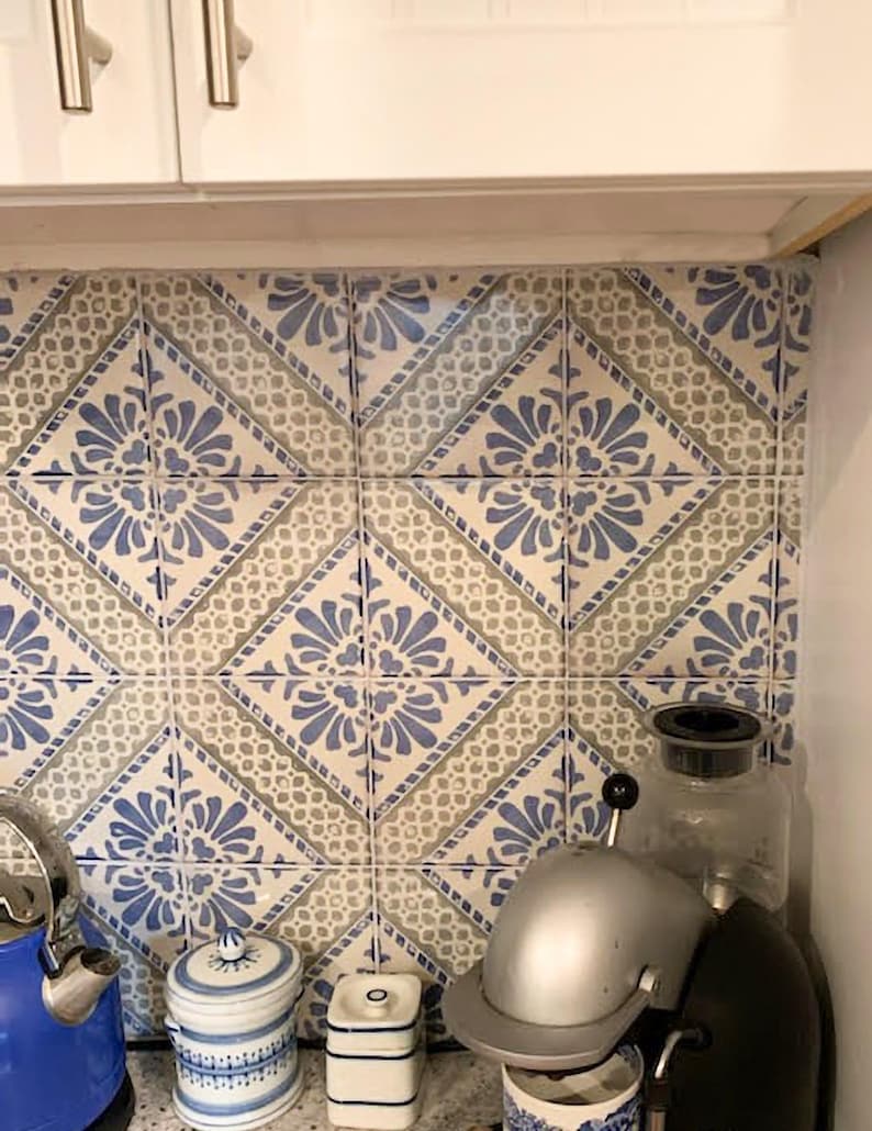 Pode incluir: Azulejos decorativos de cozinha com um padr&atilde;o floral azul e branco. Os azulejos est&atilde;o dispostos em um padr&atilde;o de losangos. Uma chaleira azul, potes e uma cafeteira s&atilde;o vis&iacute;veis na bancada.
