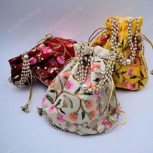 May include: Three drawstring bags with pearl trim. The bags are made of fabric and are embroidered with floral designs. The bags are in red, yellow, and cream colors.
