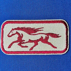 May include: A rectangular patch featuring a running horse design. The horse is red with a flowing mane and tail, set against a cream background. The patch has a red border and is set against a blue background.