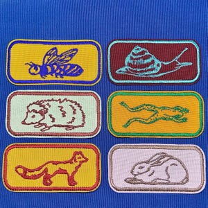 以下が含まれることがあります： さまざまな動物が描かれた刺繍のアイロン接着パッチ6枚。パッチは黄色、オレンジ、赤、茶色、緑、青です。動物には、蜂、カタツムリ、ハリネズミ、カエル、キツネ、ウサギが含まれています。