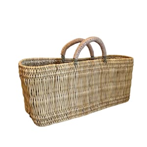 May include: A rectangular woven basket with two arched handles. The basket is made of light brown natural fibers, with a textured surface. The handles are wrapped in a lighter tan material. The basket is empty and sits against a white background.