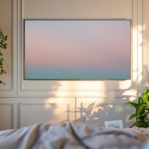 May include: A large, rectangular television screen displays a gradient of colors, transitioning from pink to teal. The screen is mounted on a wall with decorative molding. A hanging plant and potted greenery add natural elements to the room.