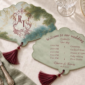 May include: Two fan-shaped wedding programs with scalloped edges and deep red tassels. One features a landscape illustration with the monogram RT in a decorative frame. The other lists a wedding schedule with the text Welcome to our wedding.