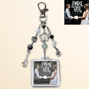 May include: A silver keychain with a clear plastic charm featuring a band photo and the text "Pierce the Veil". The charm is attached to a silver chain with black and white beads and a silver flower charm.