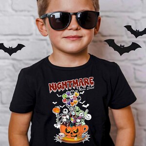 May include: A black t-shirt featuring a Halloween-themed graphic. The design includes characters from "The Nightmare Before Christmas" inside a jack-o'-lantern, with the text "Nightmare on Main Street". The shirt is worn by a person wearing sunglasses.
