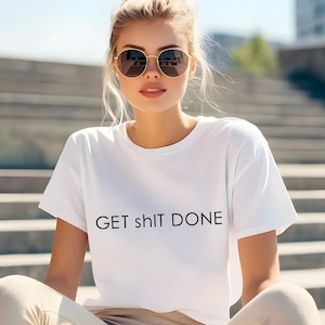 May include: A white t-shirt with the text "GET sh!t DONE" in black. The shirt is short-sleeved and is being worn by a person wearing sunglasses.