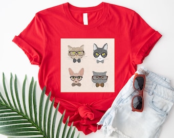May include: A red t-shirt featuring a square graphic with four cat portraits wearing glasses and bow ties. The cats are in various colors, including gray, brown, and a hairless cat. The shirt is paired with denim shorts and sunglasses.