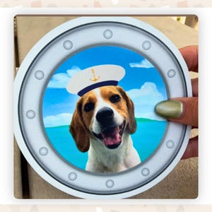 Close up of a finished porthole magnet of a beagle wearing a sailor's cap held in a woman's hand.