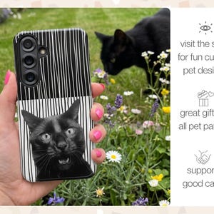 A custom Tough Case for a Galaxy S25 with a portrait of a funny black cat looking surprised against a black and white striped background. The phone is being held up in front of a garden where the real black cat is smelling the flowers. The captions read: visit the shop for more custom pet designs, great gift for all pet parents, and support a good cause.