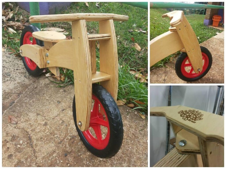 May include: A wooden balance bike with red wheels. The bike has a simple design with a wooden frame and handlebars. The seat is made of wood and is adjustable.