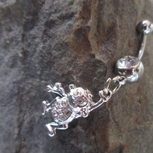May include: Silver belly button ring with a dangling charm of a frog with rhinestones.