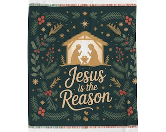 Op de afbeelding: Een donkergroene kerstdeken met een feestelijk ontwerp. De deken heeft een gouden kerststal, omringd door groenblijvende takken, rode bessen en sterren. De tekst "Jesus is the Reason" is in goud geschreven.