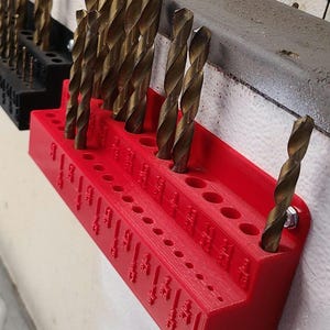 Puede incluir: Porta brocas de plástico rojo con una variedad de brocas de diferentes tamaños. El porta brocas está etiquetado con los tamaños de las brocas.