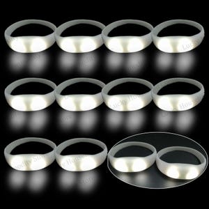 Puede incluir: Una colección de pulseras luminosas LED blancas. Cada pulsera tiene un diseño circular y flexible con una sección de luz brillante. Las pulseras se muestran sobre un fondo negro, resaltando su cualidad luminosa.
