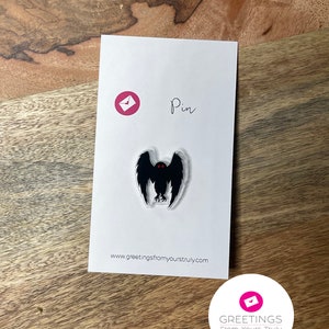 Peut inclure: Une &eacute;pingle en &eacute;mail noir et rouge repr&eacute;sentant la silhouette d'une cr&eacute;ature aux grands yeux et aux ailes. L'&eacute;pingle est sur une carte blanche avec le texte "Pin" et "www.greetingsfromyourstruly.com".