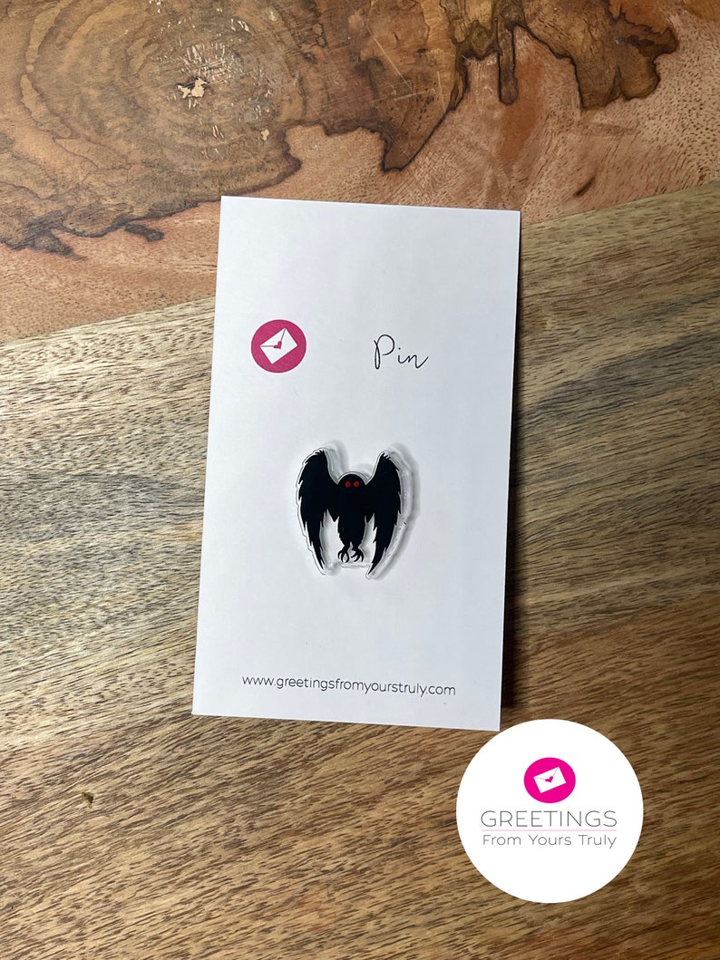 Peut inclure: Une &eacute;pingle en &eacute;mail noir et rouge repr&eacute;sentant la silhouette d'une cr&eacute;ature aux grands yeux et aux ailes. L'&eacute;pingle est sur une carte blanche avec le texte "Pin" et "www.greetingsfromyourstruly.com".
