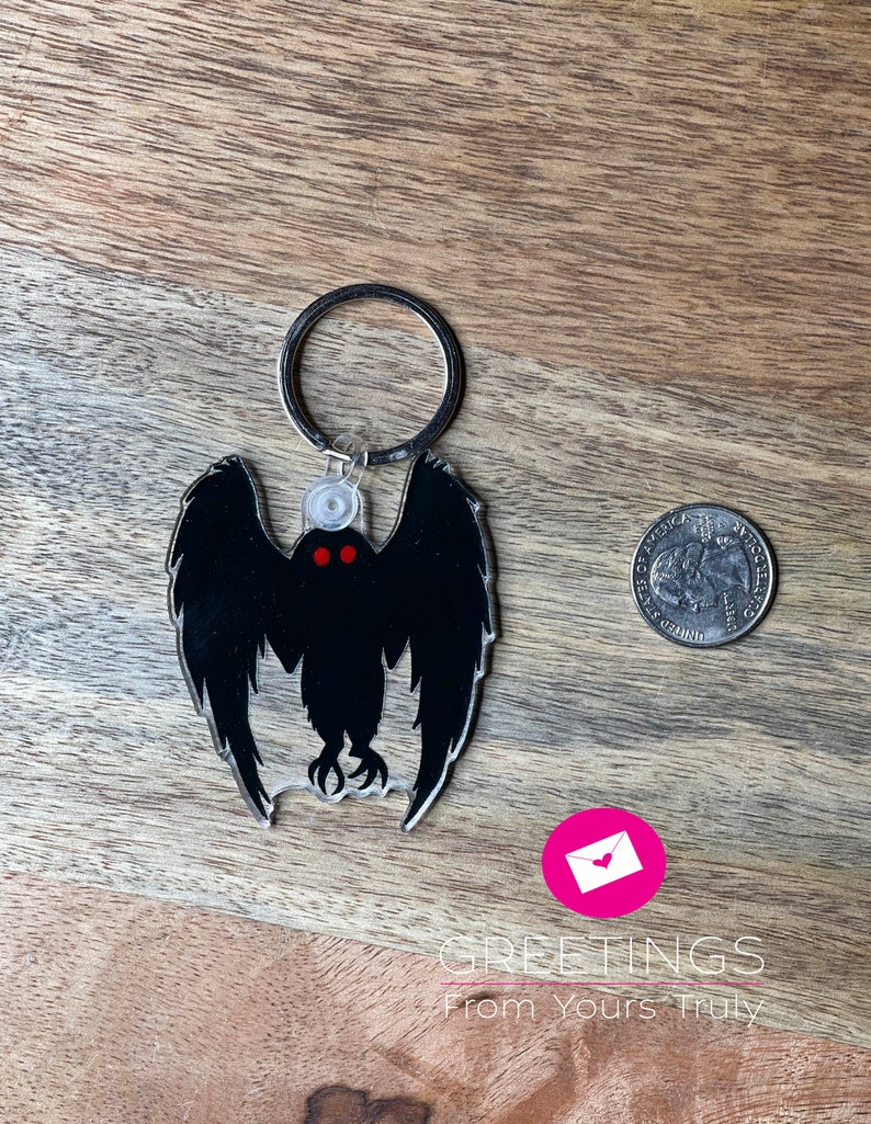 Peut inclure: Un porte-cl&eacute;s en acrylique noir et rouge repr&eacute;sentant la silhouette d'une cr&eacute;ature aux grandes ailes et aux yeux rouges brillants. Le porte-cl&eacute;s est attach&eacute; &agrave; un anneau en m&eacute;tal argent&eacute;.