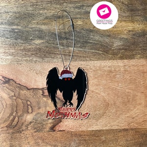 May include: A black and red Christmas ornament featuring a mothman with a Santa hat and the text "Merry Mothmas".