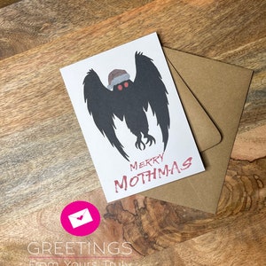 May include: A white card with a black silhouette of a mothman wearing a Santa hat. The text "Merry Mothmas" is written in red below the mothman.