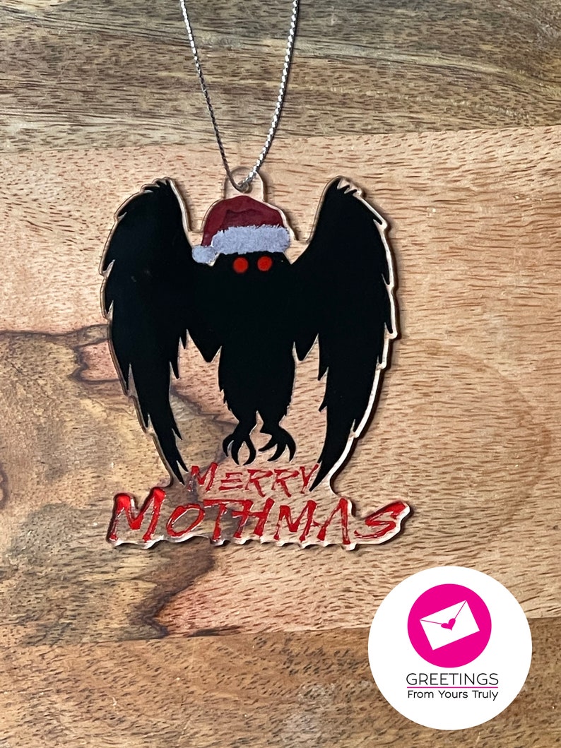 May include: A black and red Christmas ornament featuring a silhouette of the Mothman wearing a Santa hat with the text "Merry Mothmas".