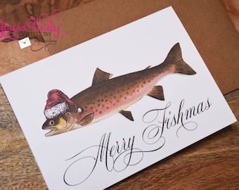 May include: A white Christmas card with a brown trout wearing a red Santa hat. The text "Merry Fishmas" is written in cursive.